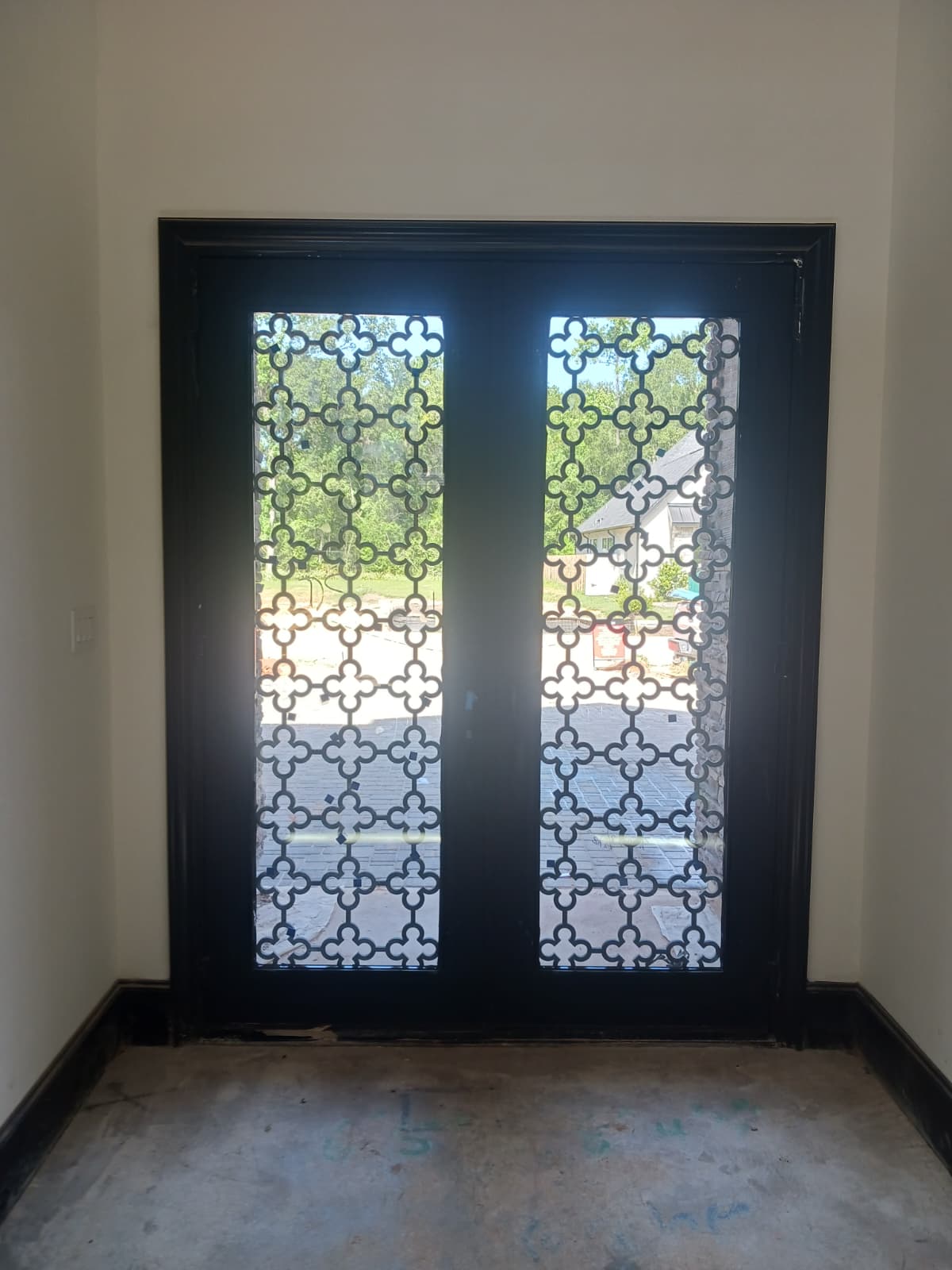 Pair of black iron entry doors with matching geometric grilles