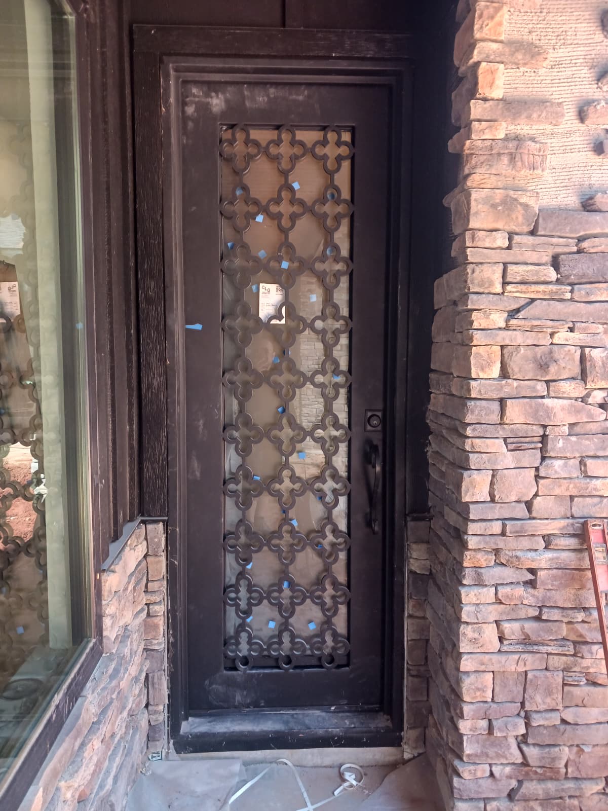 Ornate black iron entry door with geometric grille detail