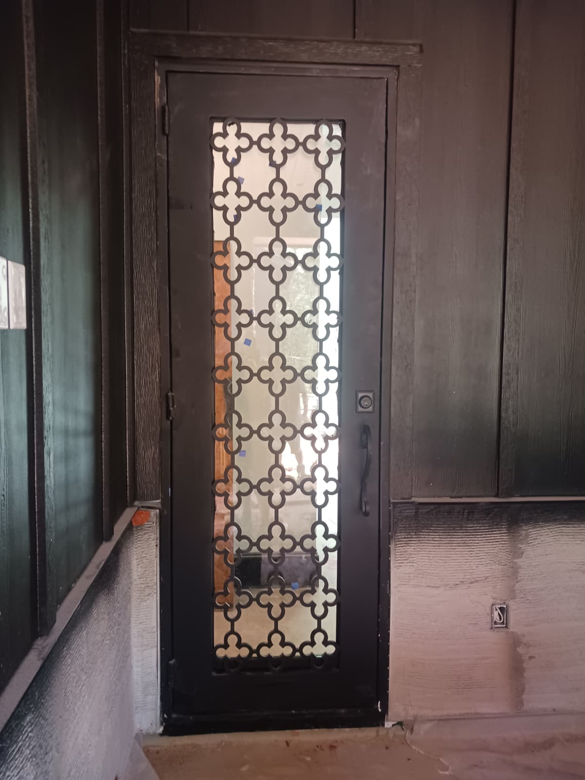 Ornate iron single entry door with geometric grille detail