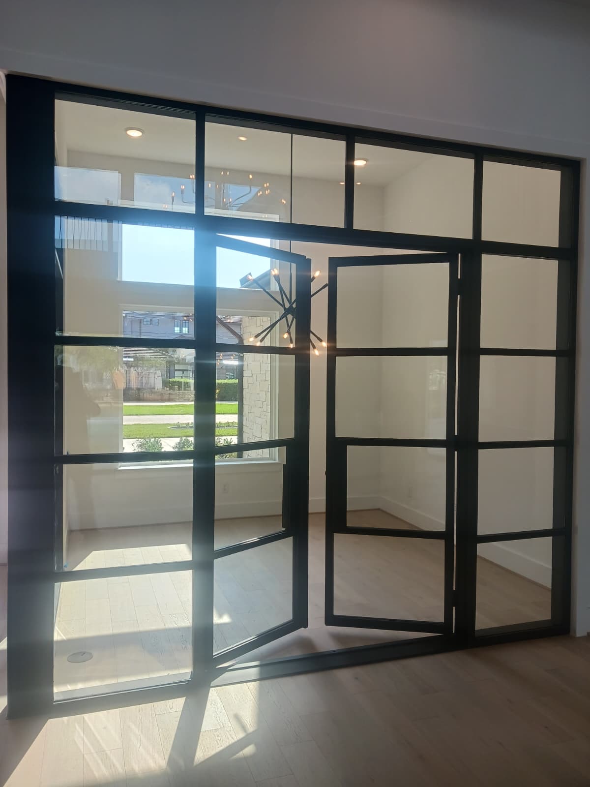 Open black steel double doors with a transom and grid glass