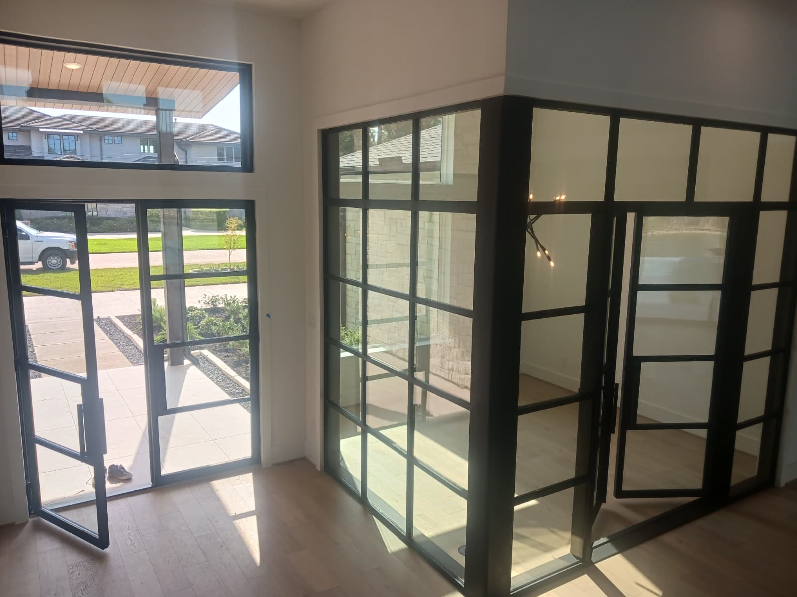 Black steel double entry doors and glass sidelights in a bright foyer