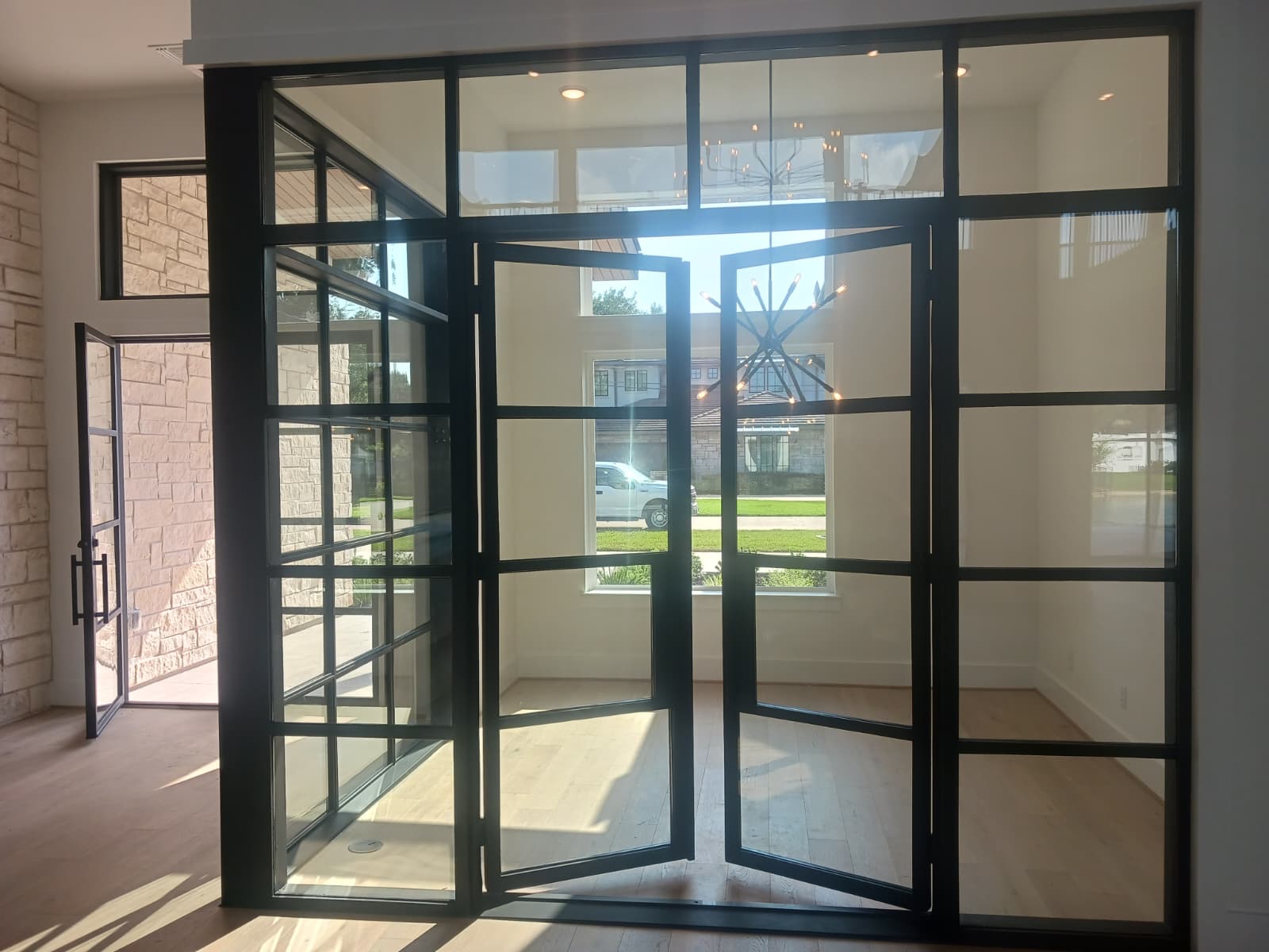 Open black steel entry doors with full-height glass walls
